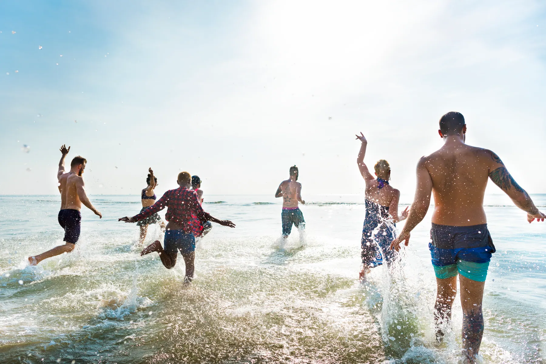 Grupo de amigos corriendo felices hacia el mar